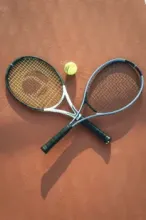 A tennis racket and tennis ball placed on a tennis court