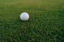 A golf ball placed on a golf course near the hole